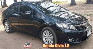 a black honda civic 1.8 litre automatic car parked beachside amongst some trees in the sand