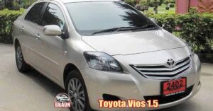 silver rental toyota vios 1.5 litre automatic parked in a landscaped phuket residential area with a low hedge to the side, manicured lawns and a villa wall in traditional thai style, deep pink with gold reliefs